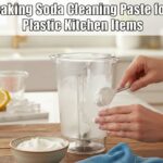 A person applies a thick baking soda cleaning paste for plastic kitchen items to a foggy blender jar on a sunny kitchen counter.