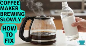 A coffee maker brewing slowly and steaming on a kitchen counter, with a hand holding a bottle of white vinegar for repair.