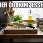 A rustic kitchen counter showing beginner cooking essentials like a cast iron skillet, a sharp chef knife, a wood cutting board, a coffee maker, and fresh sourdough bread.