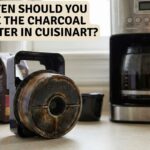 Used Cuisinart charcoal water filter in black plastic holder sitting on kitchen counter next to a calendar marked replace filter and a coffee maker.