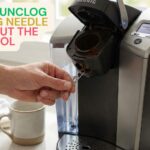A person using a straightened paperclip to unclog the exit needle inside a Keurig coffee maker pod holder.
