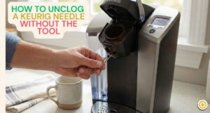 A person using a straightened paperclip to unclog the exit needle inside a Keurig coffee maker pod holder.