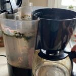 Close-up of a dirty coffee maker water reservoir showing pink slime and green mold spots inside the tank.