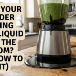 A stainless steel blender leaking from bottom black liquid onto a wooden kitchen counter next to a repair wrench.