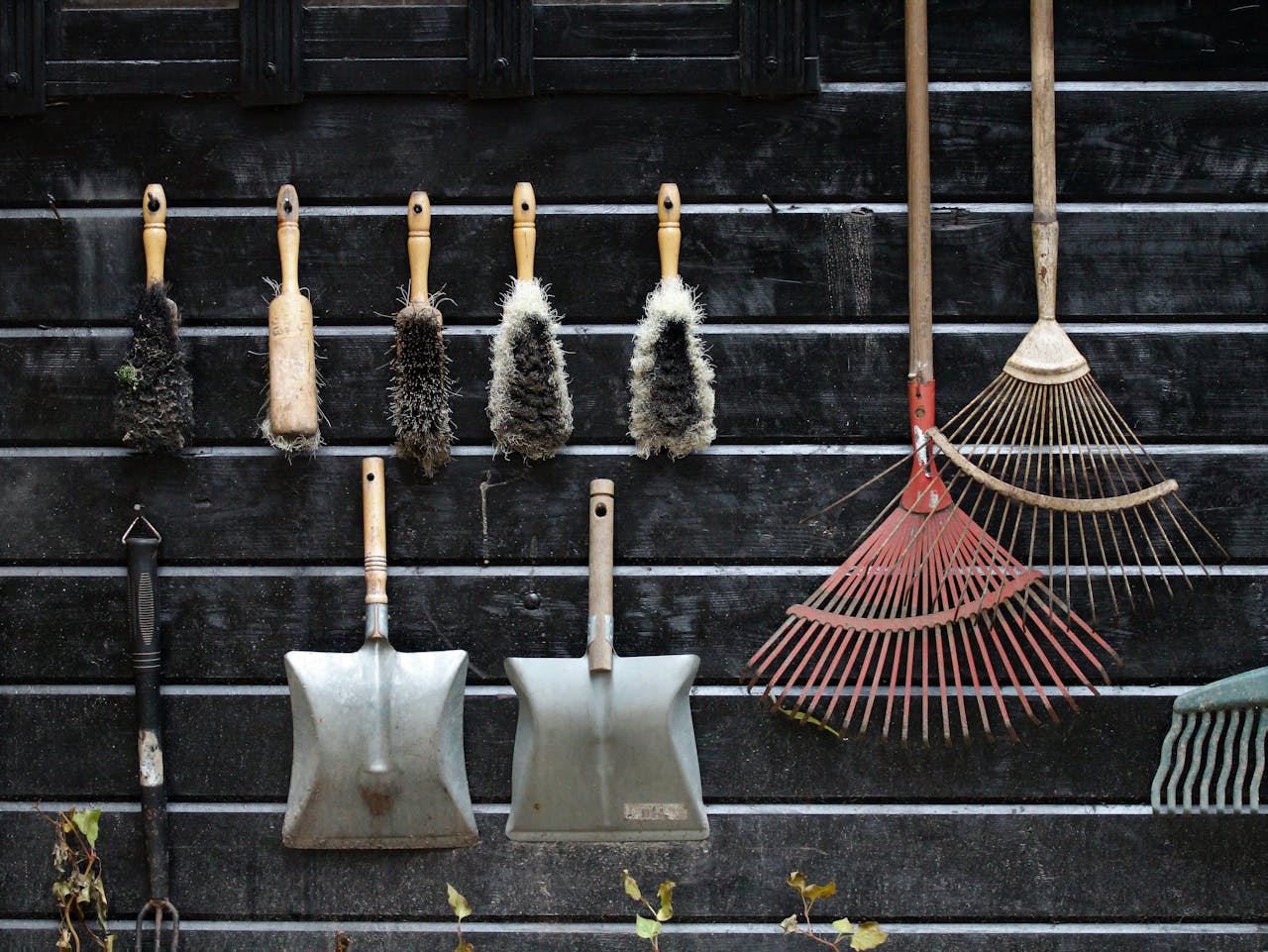 hero-img Neatly arranged garden tools hanging on a rustic wooden wall.