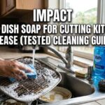 A person scrubbing a greasy metal air fryer grate in a kitchen sink with a blue sponge and soapy water to demonstrate the best dish soap for cutting kitchen grease.
