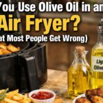 Air fryer with fries and chicken wings beside bottles of extra virgin and light olive oil, with headline text about using olive oil in an air fryer.