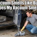 A man in a garage looking confused at a smoking handheld car vacuum next to his truck, with the text "Car Vacuum Smells Like Burning: Why Does My Vacuum Smell Bad?" overlaid at the top.