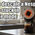 A tabby cat pawing at a Nespresso Vertuo machine with a bright red and yellow glowing light ring on a kitchen counter.