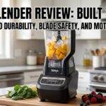 A Ninja Professional Plus blender on a kitchen counter with frozen fruit and spinach. Bold text reads: Ninja Blender Review: Built to Last?