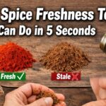 Kitchen scene with jars of colorful spices on a wooden counter and bold Impact font text reading “Simple Spice Freshness Test You Can Do in 5 Seconds.”
