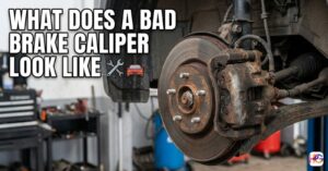 A rusty and corroded car brake caliper mounted on a worn rotor in a workshop, showing what a bad brake caliper looks like with visual signs of neglect and age.