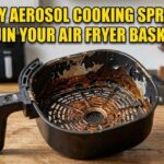 A peeling black air fryer basket next to a spray can.