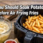 Bowl of raw potato fries soaking in cloudy water beside an air fryer basket with text “Why You Should Soak Potatoes Before Air Frying Fries”