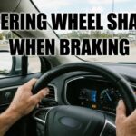 A person holds a steering wheel tightly on a busy highway with big text that says steering wheel shakes when braking.