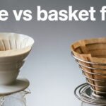 Cone vs basket filter comparison showing white ceramic cone dripper and metal basket filter with brown paper filters over glass carafes