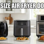 A comparison of three different-sized air fryers lined up on a white kitchen island. From left to right: a small, compact, round black air fryer with a knob is paired with a plate of french fries; a medium, square dark grey digital air fryer is paired with a plate of chicken and vegetables; a large, stainless steel and glass air fryer oven with multiple racks is paired with a whole roasted chicken platter. Bold white text across the top with a black outline reads "WHAT SIZE AIR FRYER DO I NEED". The background shows a modern, bright kitchen.