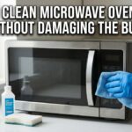 A person wearing a blue rubber glove carefully wipes a stainless steel microwave oven touch pad with a blue cloth next to a bottle of rubbing alcohol.
