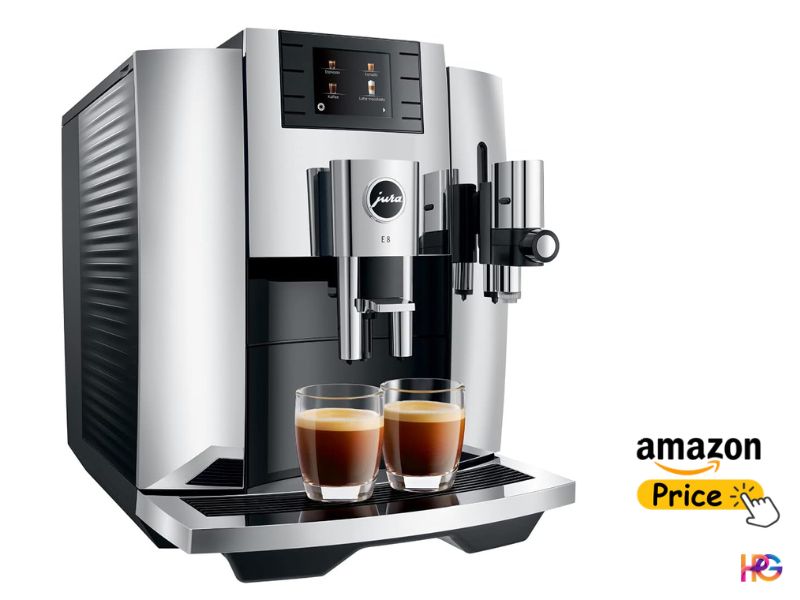 An angled, three-quarter view of a silver and black Jura E8 automatic coffee machine against a pure white background. The machine features a detailed, fluted side panel and a central touchscreen interface with drink icons. Two glass demitasse cups with dark espresso and crema sit on the chrome-plated drip tray beneath the spouts.
