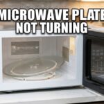 A countertop microwave with an open door showing a tilted glass tray inside, with large text overlay that reads "MICROWAVE PLATE NOT TURNING".