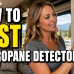 American woman inside an RV pressing the test button on a propane gas detector mounted on the wall, with large Impact-style text reading "How to Test RV Propane Detector."