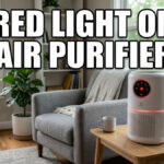 A white cylindrical air purifier with glowing red indicator lights sits on a wooden table in a sunlit living room next to an armchair and plants. Large, bold, white text at the top center reads: "RED LIGHT ON AIR PURIFIER".