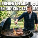 An American man uses long metal tongs to move thick ribeye steaks on a charcoal kettle grill during a backyard barbecue, managing a small flame flare-up on the grates.