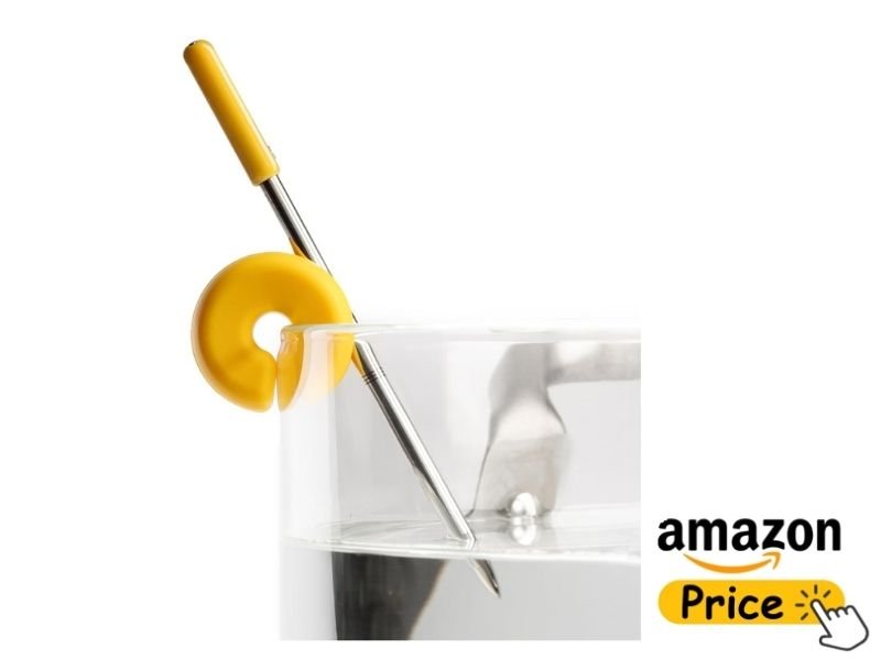 A close-up view of the Combustion Predictive Thermometer probe resting inside a clear glass of water on a white background. The probe features a bright yellow handle and a matching yellow circular clip holding it against the rim of the glass. A yellow "Amazon Price" button graphic sits in the bottom right corner.