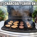 A gas grill on a backyard patio with burgers and chicken breasts cooking on the grates, alongside a metal smoker box filled with smoking wood chips. The text "HOW TO GET CHARCOAL FLAVOR ON GAS GRILL" is written across the top in white Impact font.