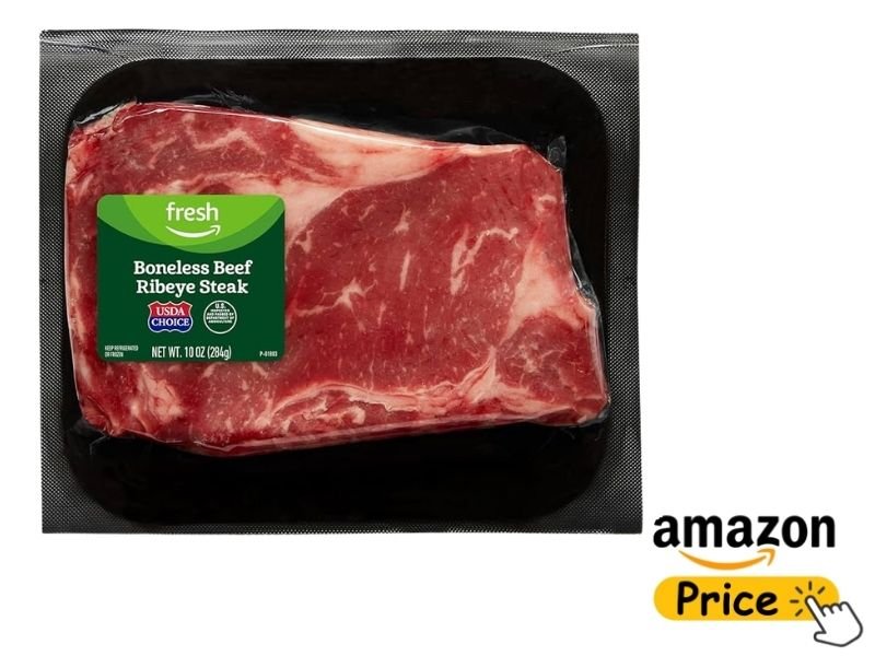 A store-packaged Amazon Fresh Boneless Beef Ribeye Steak sealed in a black plastic tray under transparent film.