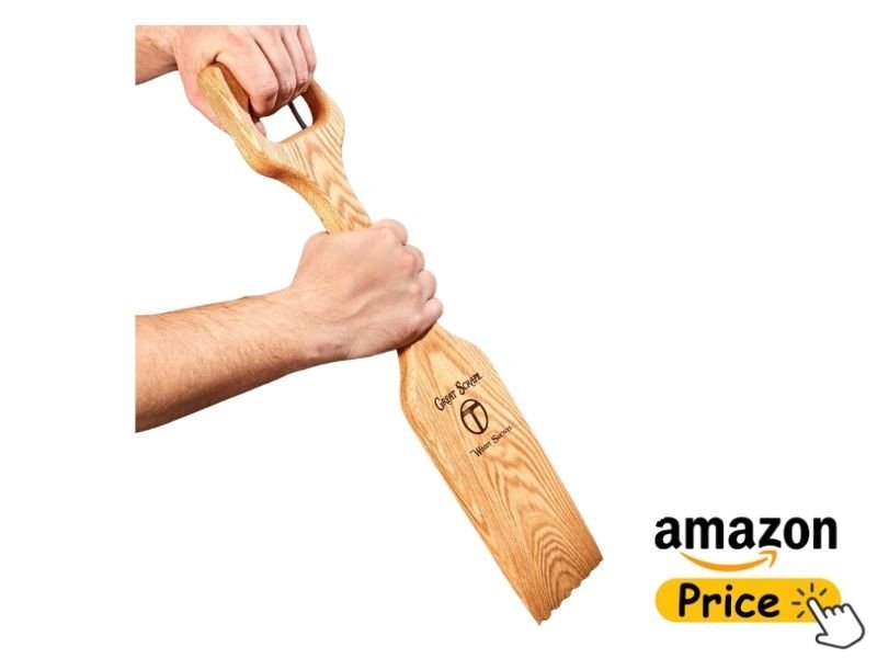 A person's hands firmly gripping the handle of The Great Scrape Woody Shovel wood paddle scraper tool against a white background with an Amazon price badge.