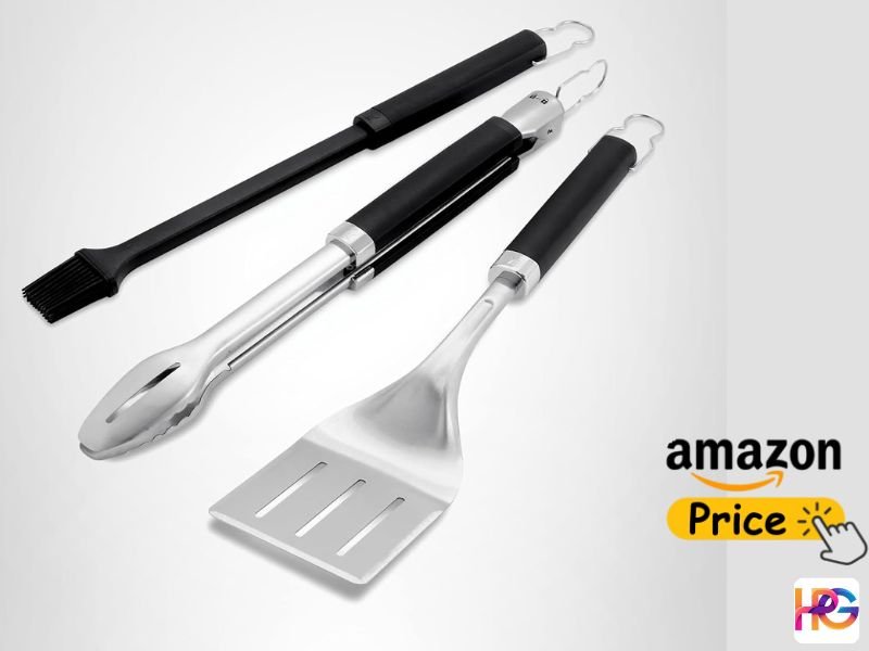 A heavy-duty three-piece stainless steel grilling set featuring long-handled tongs, a wide-headed spatula with cutting slots, and a black basting brush, displayed diagonally against a plain gray background.