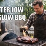 A man wearing a black apron and heat-resistant gloves bastes a large cut of smoked meat on a black offset smoker in a backyard. Large white text overlaid on the scene reads "MASTER LOW AND SLOW BBQ".